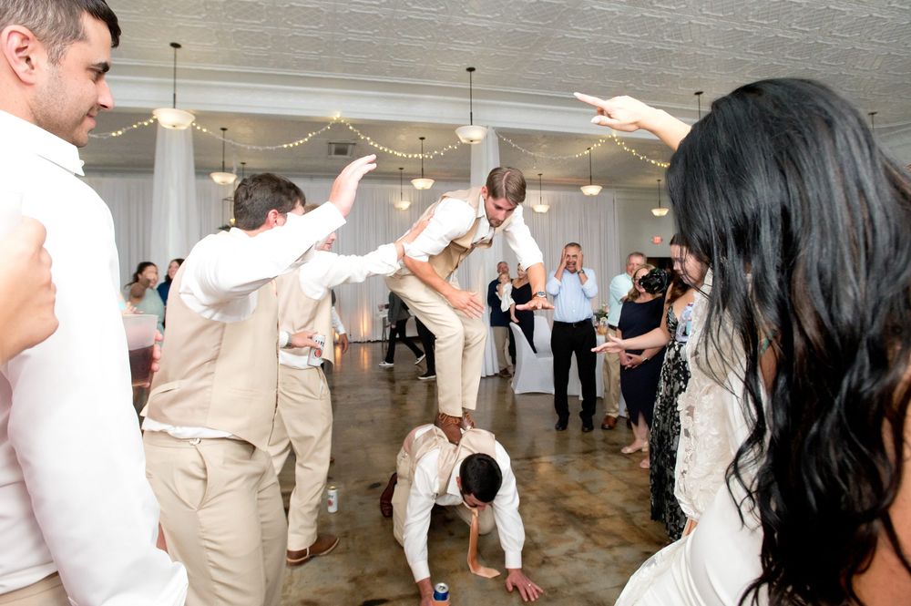 Wedding guests celebrating on the dance floor with energetic moves during a lively reception party.