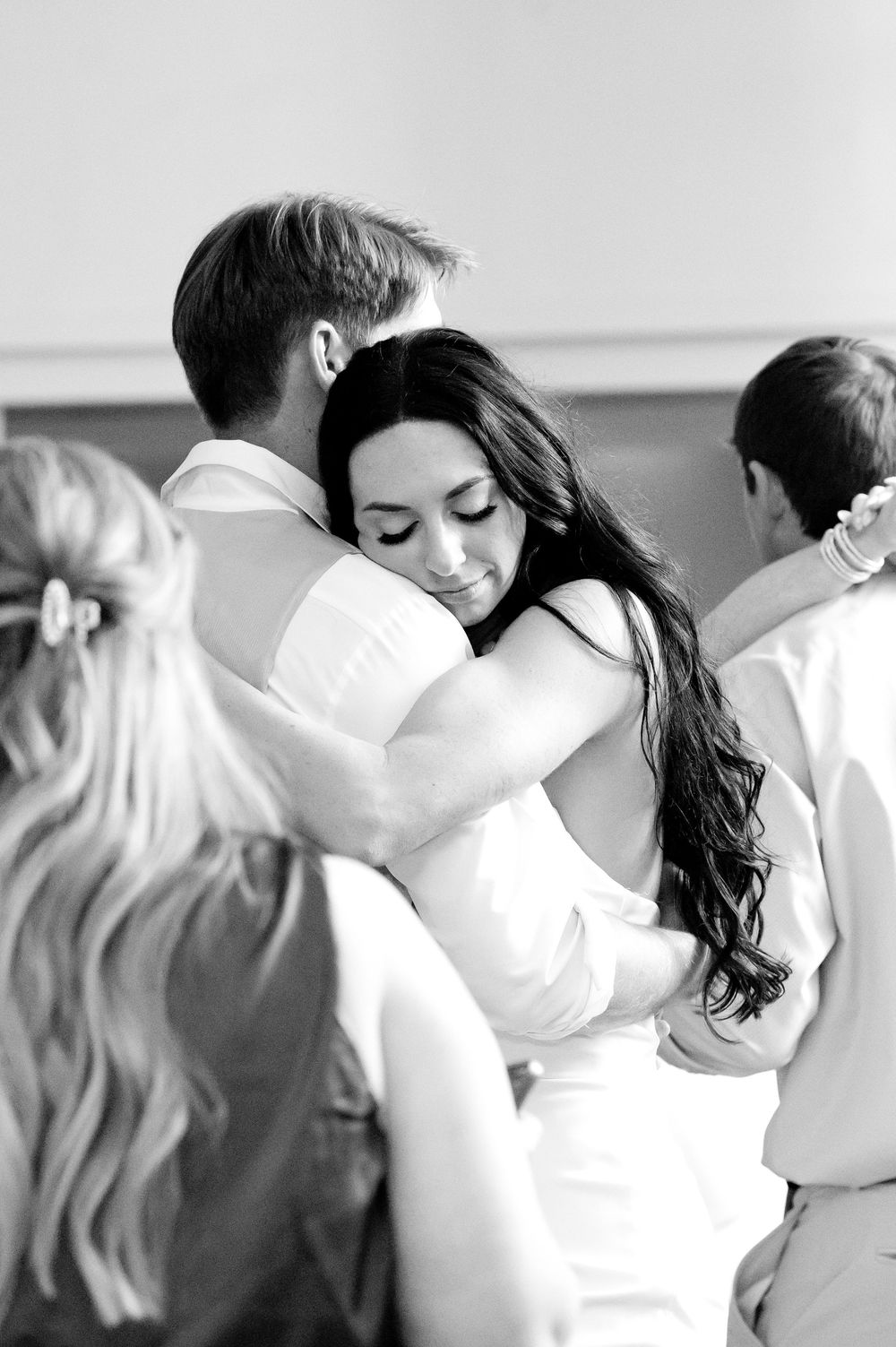 Black and white photo of a bride and groom sharing a tender embrace on their wedding day.