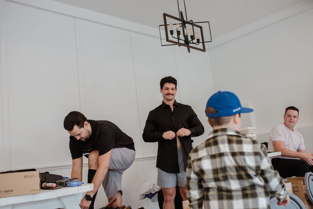 A group of people gather in a bright modern room with white walls and a contemporary light fixture overhead.