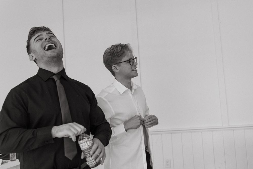A group of people laughing together while wearing formal attire in a black and white photograph.