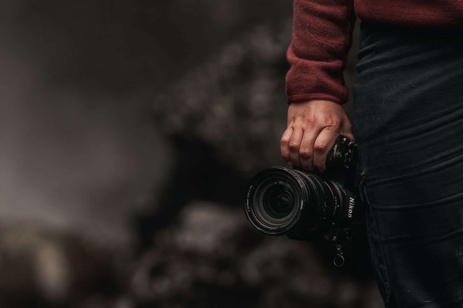 A woman holds her camera at her side.