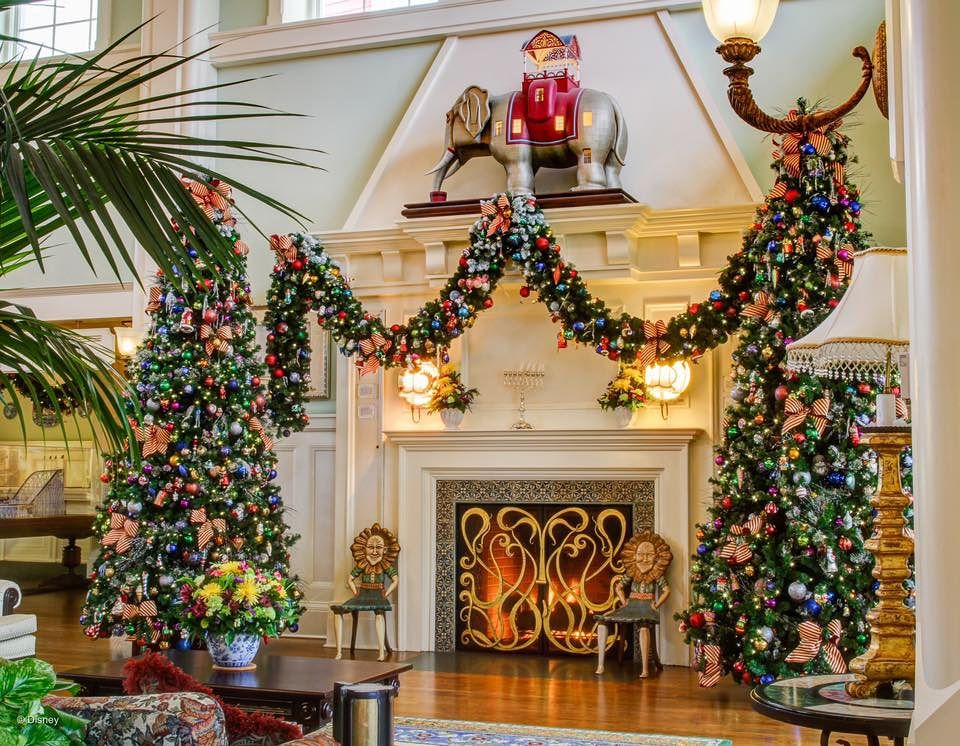 Elegant hotel lobby decorated with multiple Christmas trees and holiday decorations.