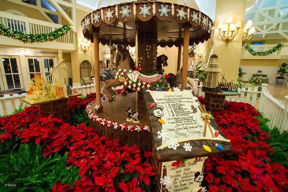 Holiday carousel display surrounded by vibrant red poinsettias and festive Christmas decorations.