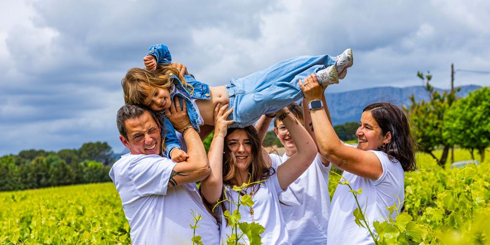 Parents soulevant leur enfant dans un champ d’iris lors d’une séance photo famille en Provence