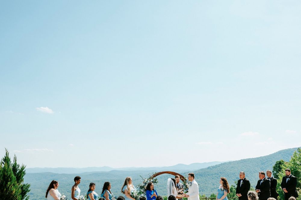 Wedding ceremony at scenic mountain overlook with circular arch and gathered guests outdoors.