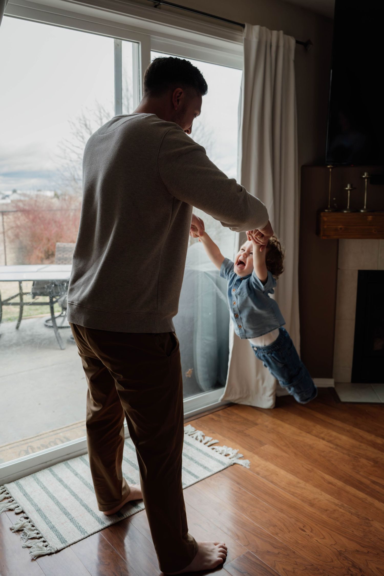 Dad swinging toddler during a playful in-home family photography session in Spokane, Washington.