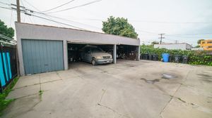 Spacious concrete driveway with covered carport garage housing a silver SUV, adjacent to a teal garage door.