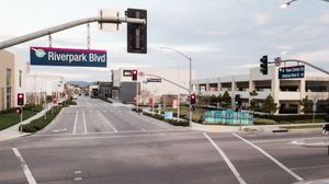 Riverpark Blvd street intersection with traffic lights, commercial buildings, and clear skies in Fresno, California.