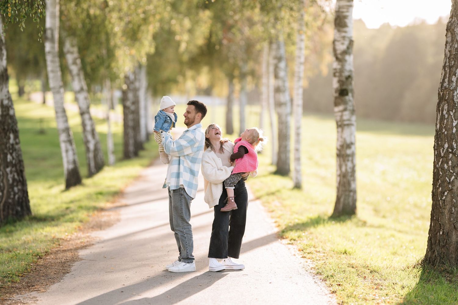 Familie in einer grünen Allee lachend und am Spaß haben.