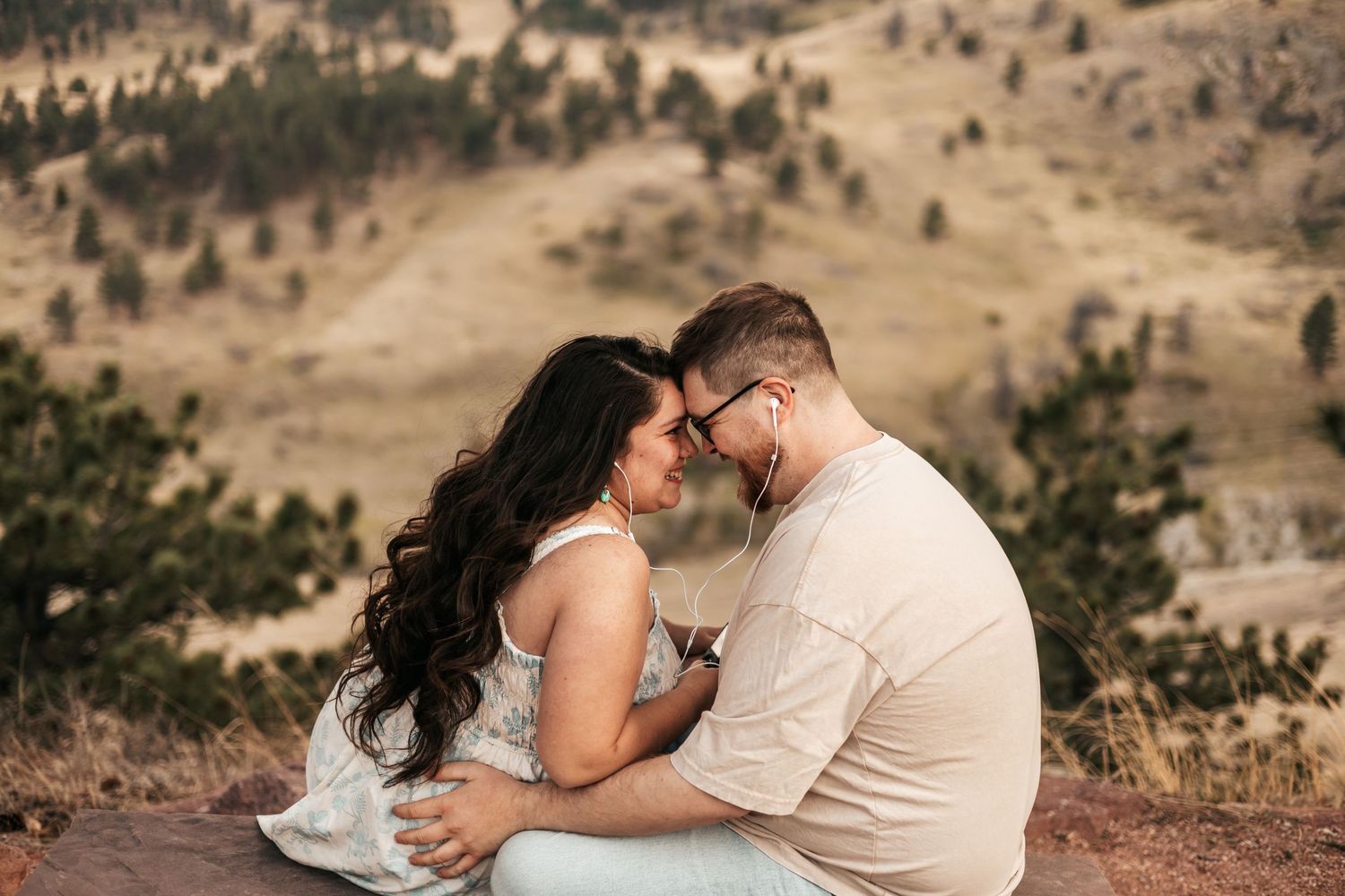 Couple sharing a romantic moment touching foreheads while sitting on a rocky overlook mountains  | Couple Photos in Boulder, Colorado