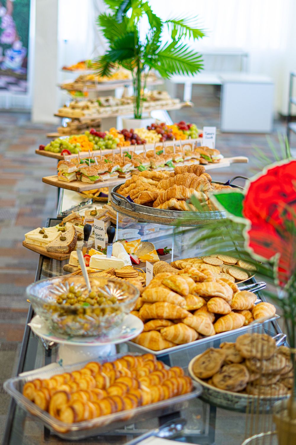 Elegant catering buffet table with croissants, pastries, cookies, and fresh fruit platters at an event.