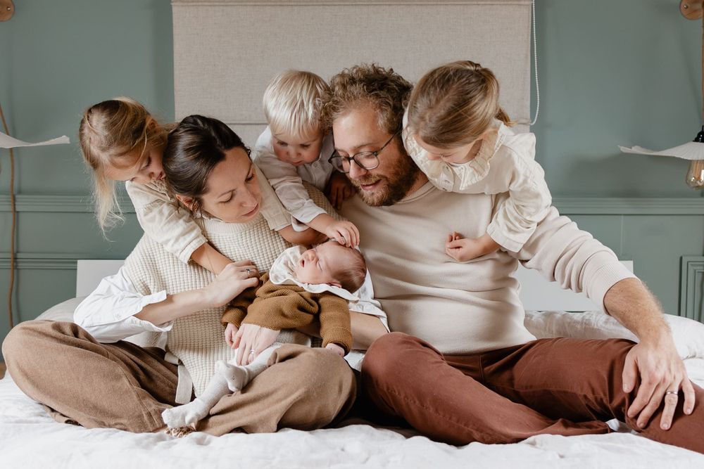 portrait d'une famille nombreuse accueillant une nouvelle petite soeur dans le foyer en seance photo de famille a domicile