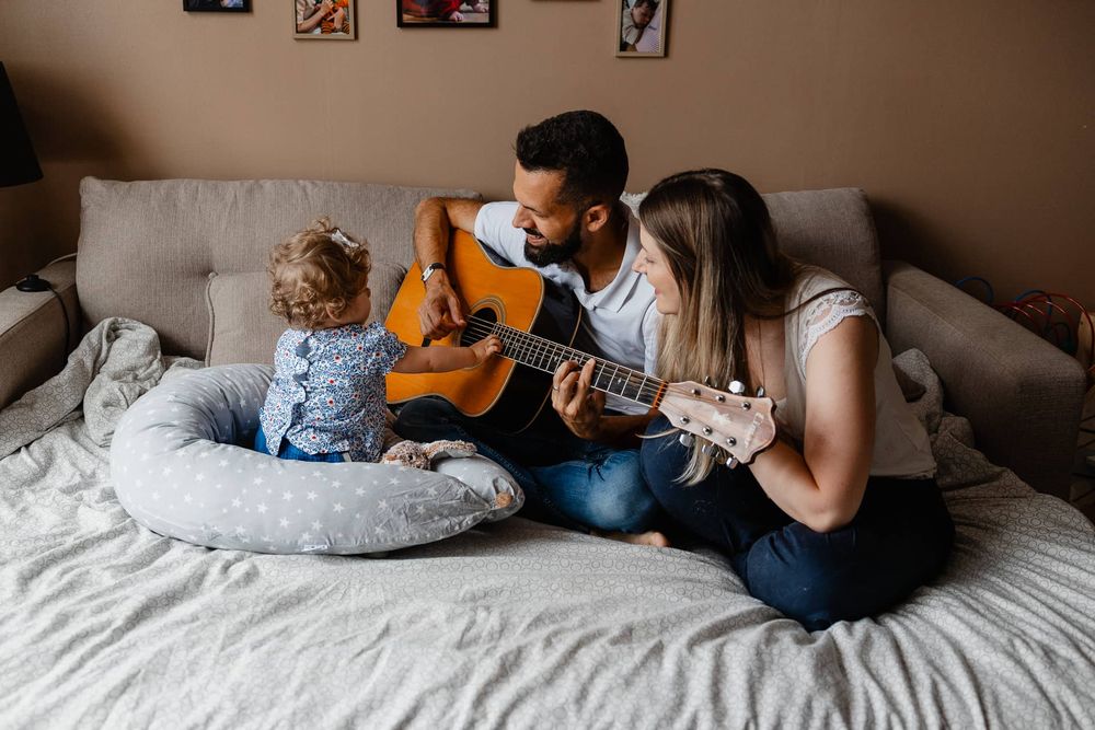 petite fille joue de la guitare avec ses parents pendant un reportage photo de famille a domicile a Lambersart pres de Lille