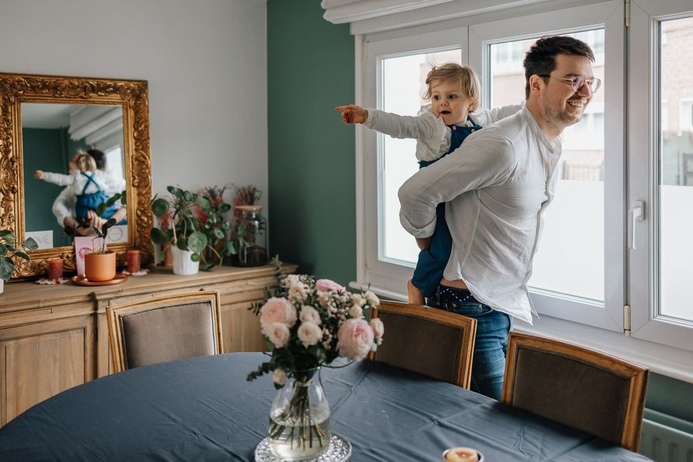 photographe de famille a Lille capture l'image d'une petite fille jouant sur le dos de son papa comme sur un cheval