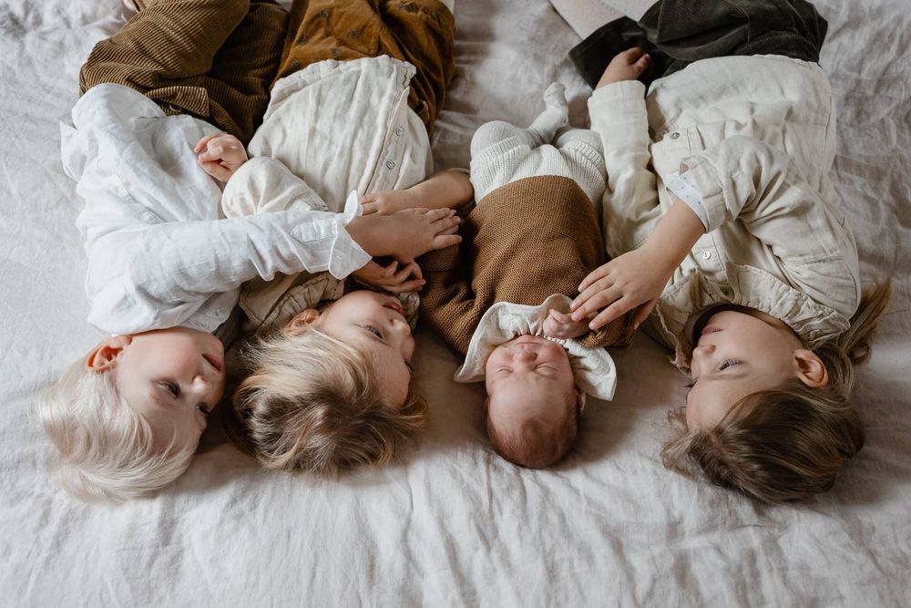 freres et soeurs se font un calin sur le lit familial pendant une seance photo de famille a Marcq en Baroeul pres de Lille, un moment tendre