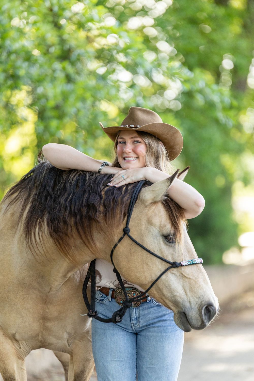 girl standing next to her horse looking over it with her hands and arms resting on the horse's neck