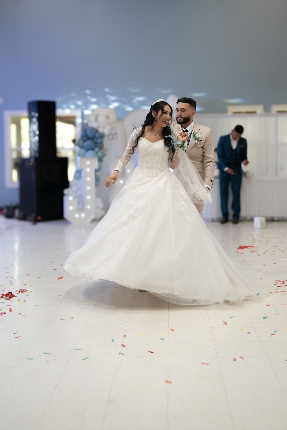 Bride and groom share their first dance, surrounded by confetti on a white dance floor at their wedding reception.