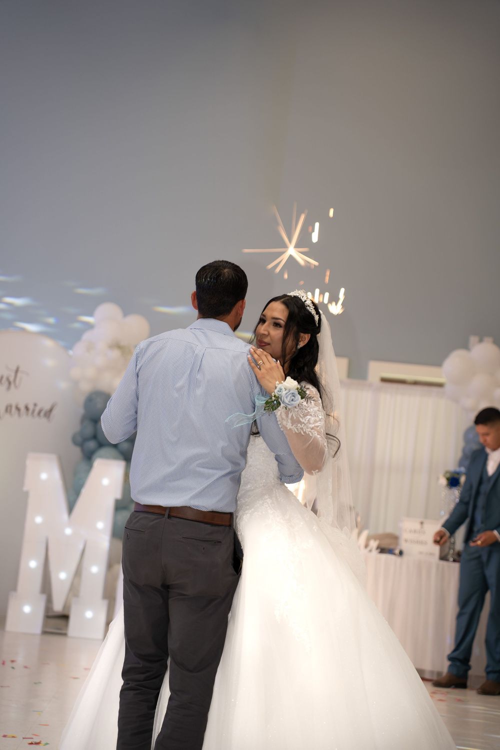 Bride and groom share first dance surrounded by balloon decor and sparkling lights at wedding.