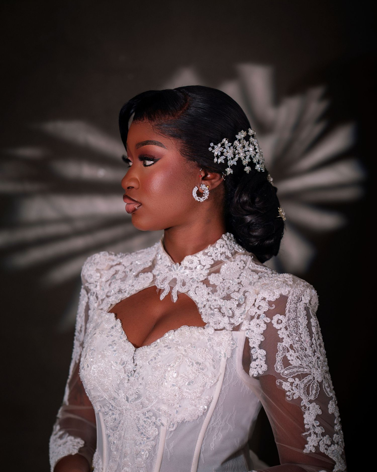 Elegant bride in white lace gown with crystal hair accessories and earrings, wearing a high-neck embroidered wedding dress.