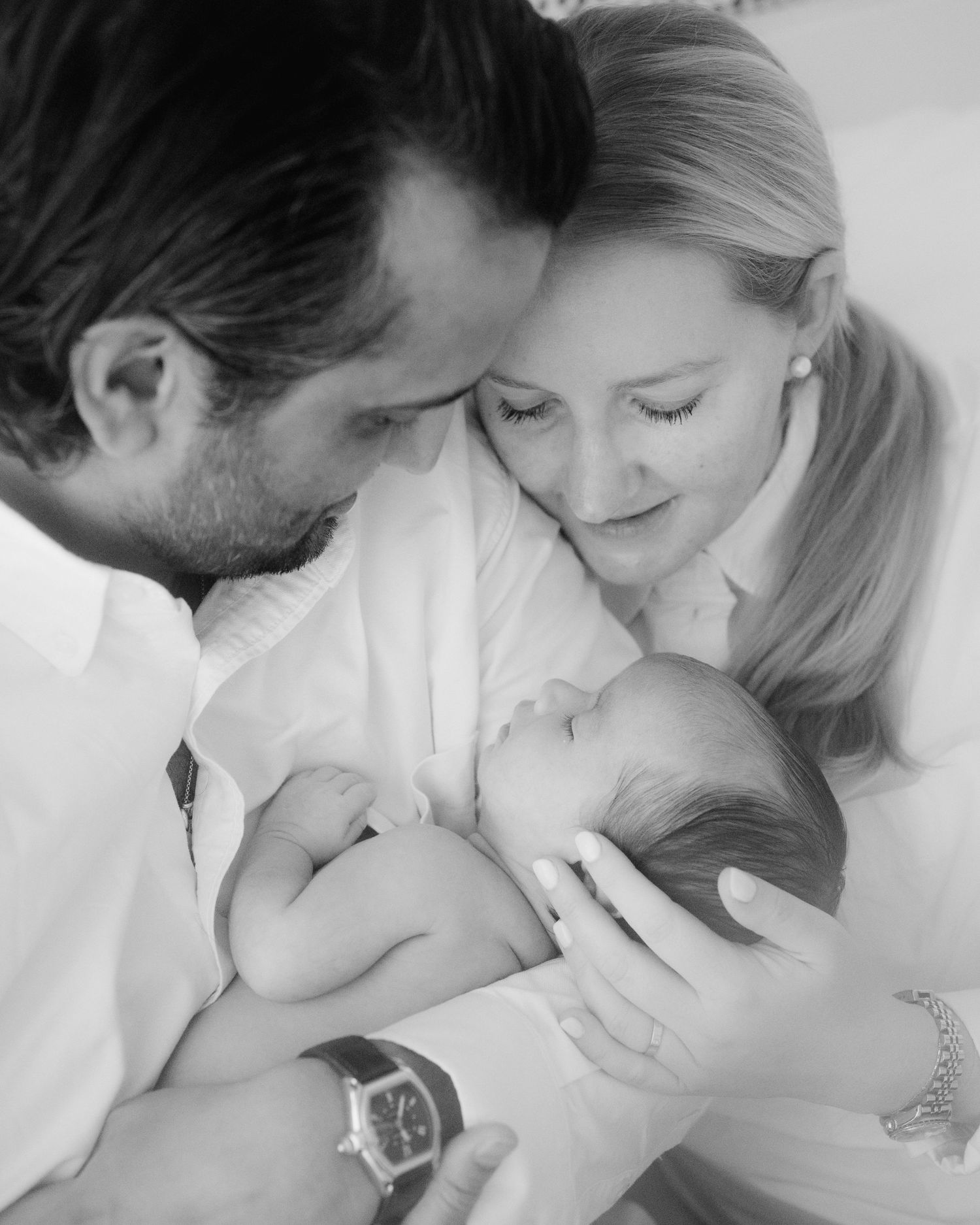 Parents smiling over their sleeping newborn baby at home, newborn family photography in Vancouver
