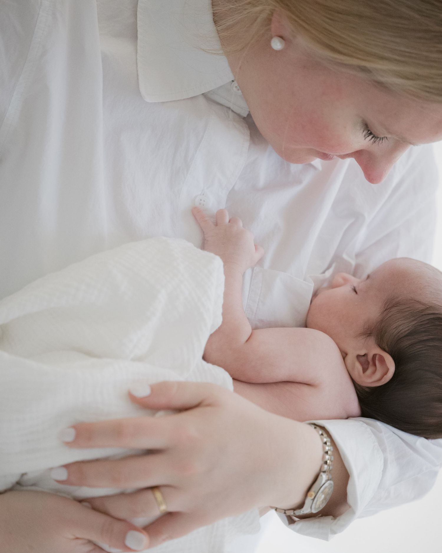 Mother gazing at sleeping newborn baby by window, cosy newborn photography North Vancouver
