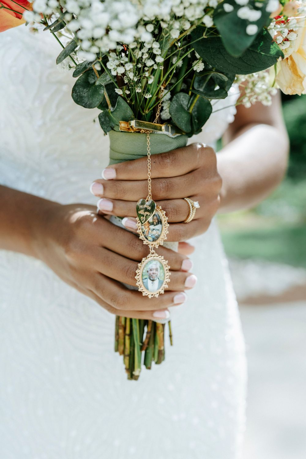Close-up of a bride holding a colorful bouquet with memorial photo locket charms honoring loved ones on her wedding day.