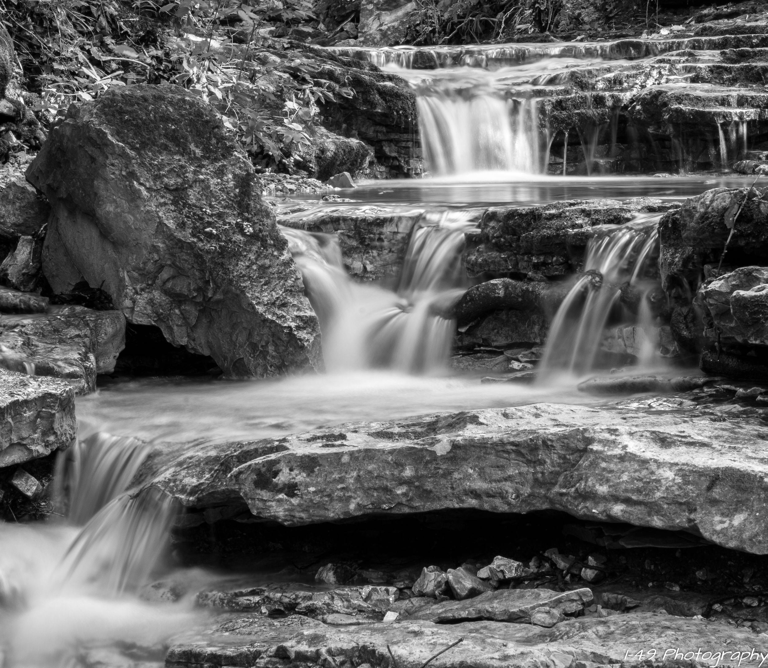 Multi-tiered waterfall cascading over rock shelves black and white long exposure near Eureka Springs, Arkansas.