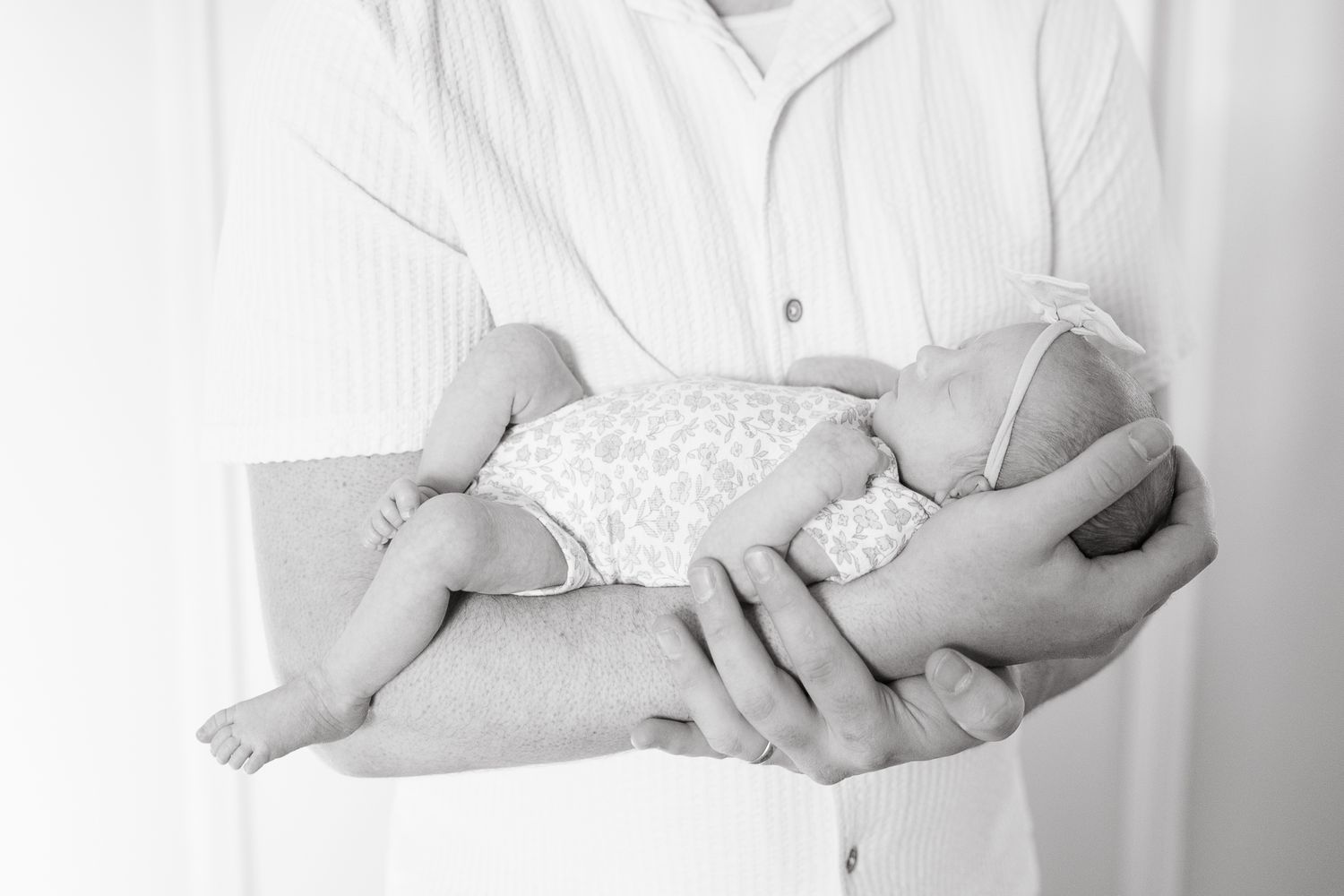 baby girl resting in the arms of her father fitting perfectly across his arm with little toes exposed photographer overland park ks