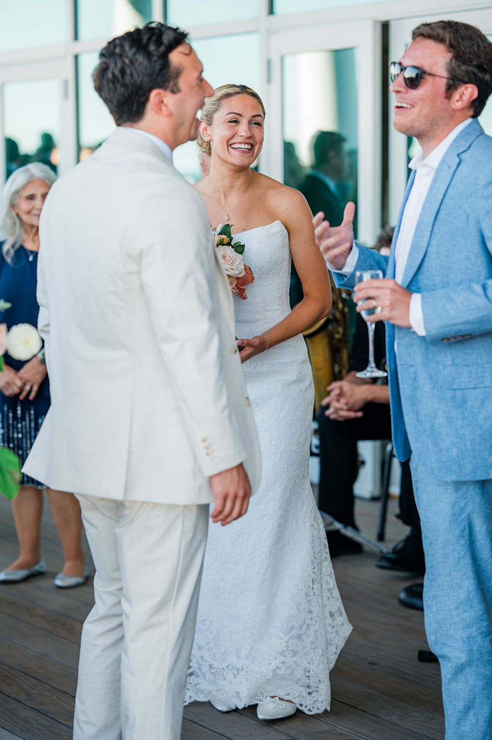 Wedding guests in light blue and white attire dancing and celebrating at an indoor reception.