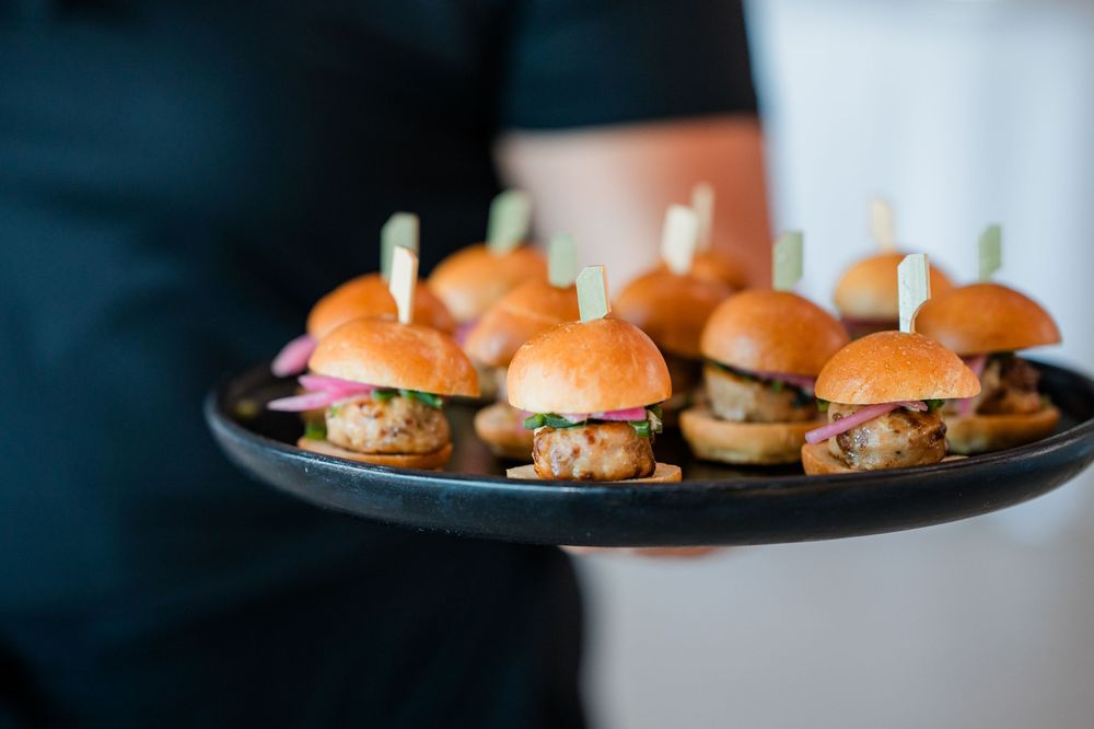 Appetizing mini sliders with meat patties and buns arranged on dark plates in a restaurant setting.