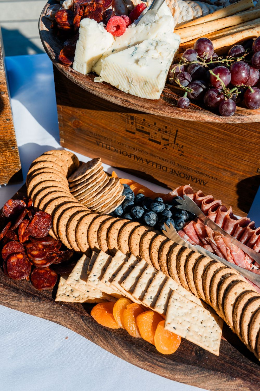 Rustic wooden charcuterie board with arranged crackers, dried fruits, grapes, and cheese for elegant party appetizers.