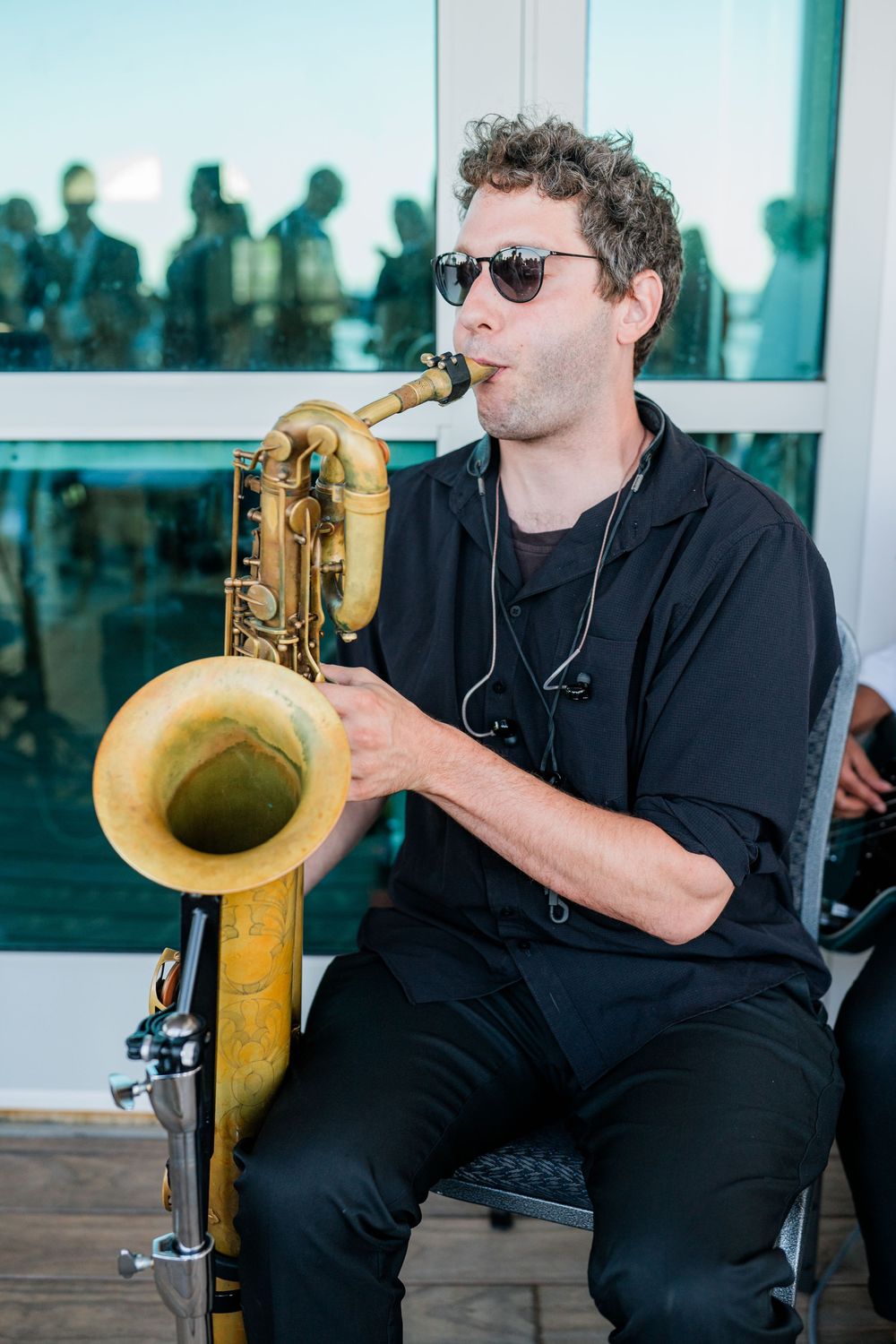 Musician in black attire playing a saxophone during a performance.