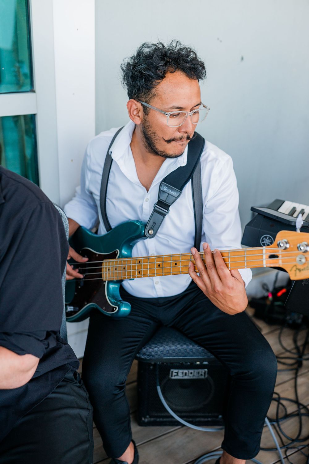 Guitarist in white shirt performing on an electric bass guitar.