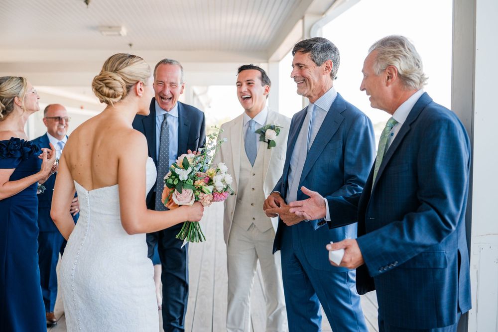 Wedding party gathering in a bright indoor venue with white decor and formal attire.