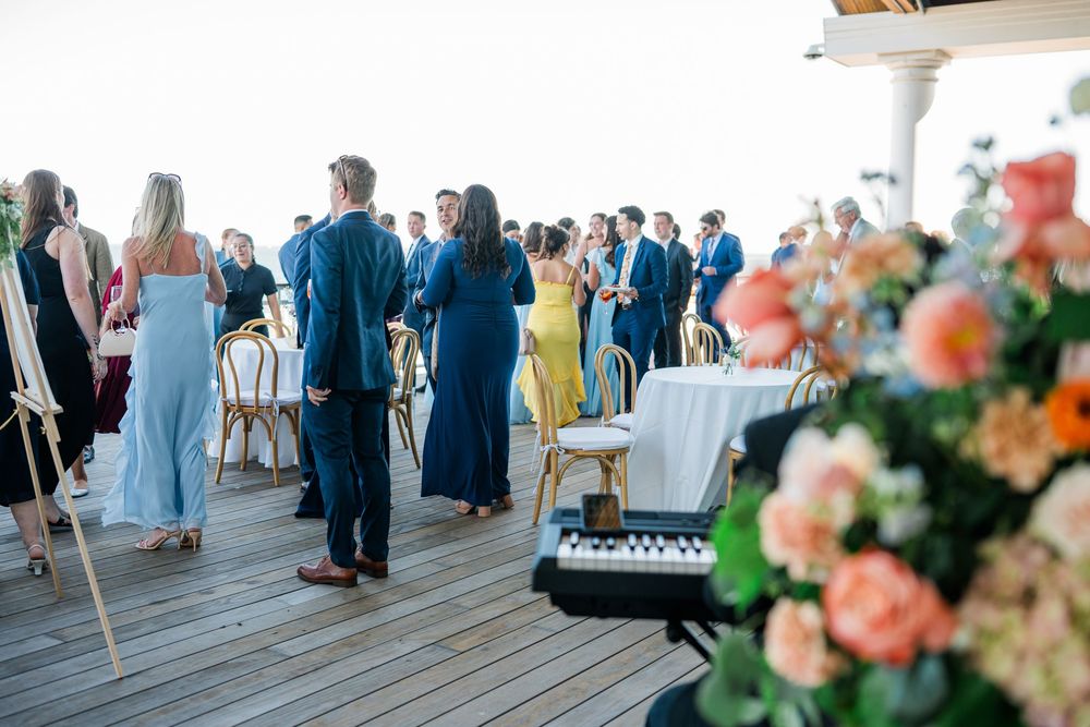 Reception celebration under white tent with peach floral arrangements and mingling guests.
