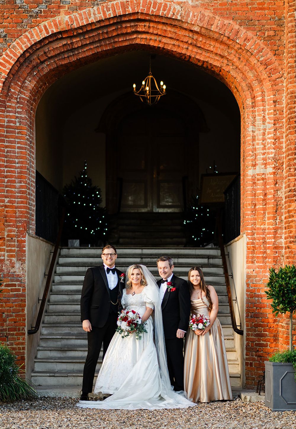 A wedding party poses under a series of brick archways at a rustic venue during a formal celebration.