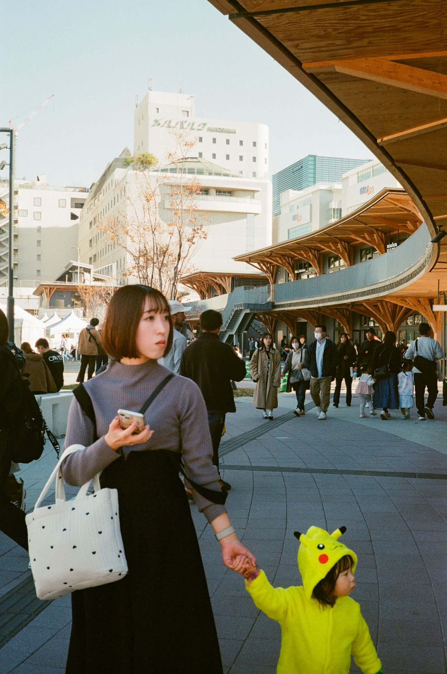A series of photos showing people walking and interacting under curved wooden architectural structures in an urban plaza.