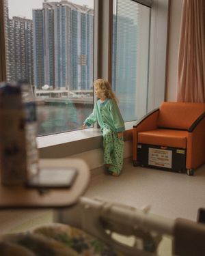 Hospital room with large windows overlooking city skyline.