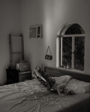 Black and white photo of a serene bedroom with arched window and minimal decor.
