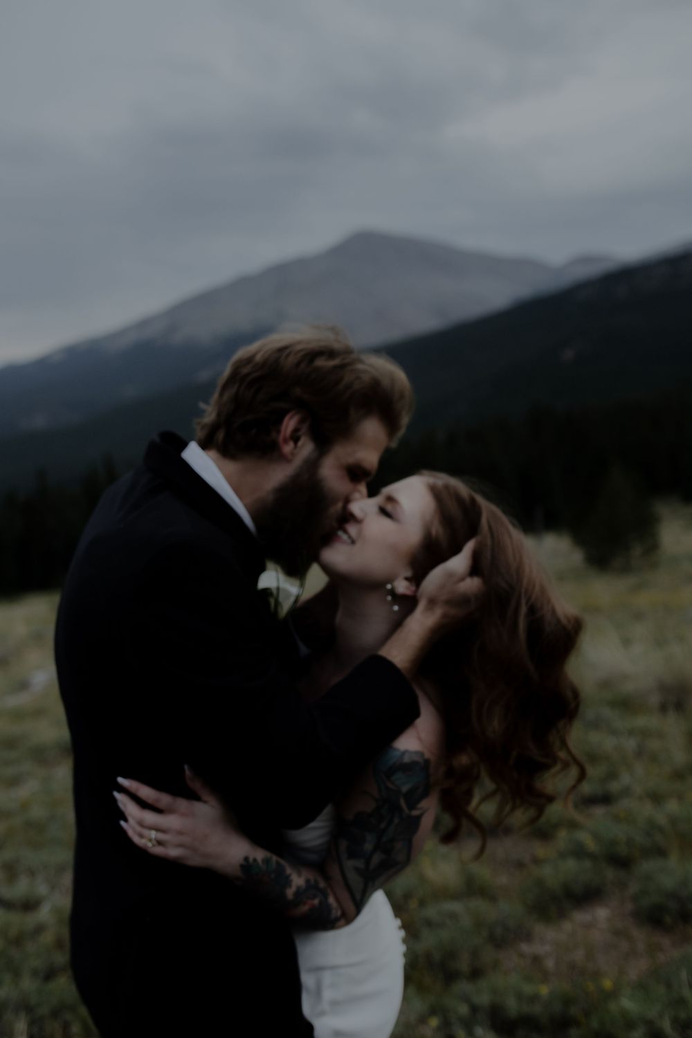 An intimate wedding portrait with dramatic mountain scenery and moody lighting.