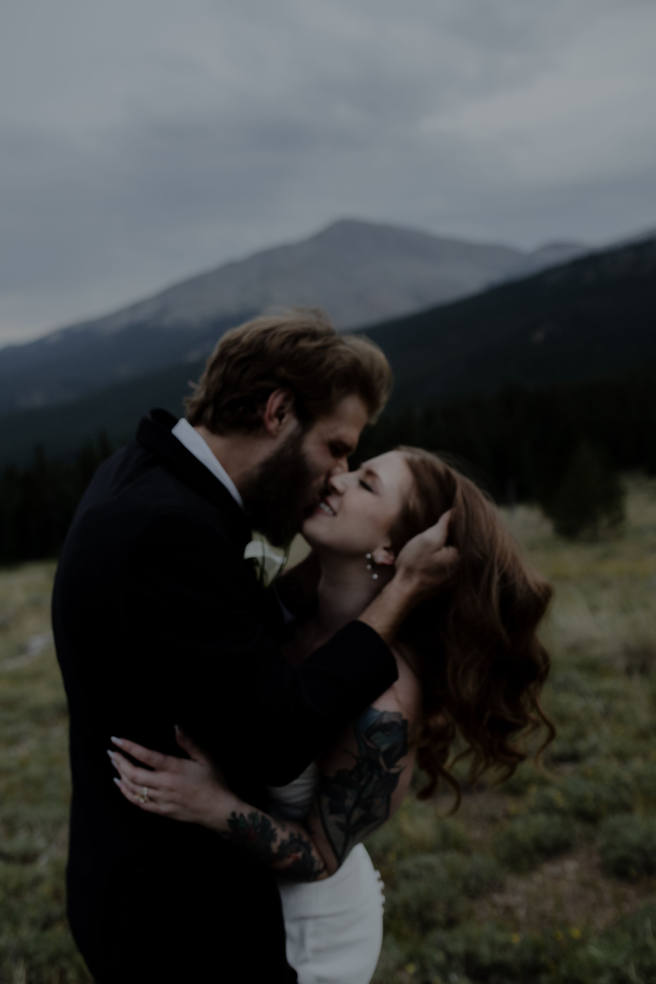 An intimate wedding portrait with dramatic mountain scenery and moody lighting.
