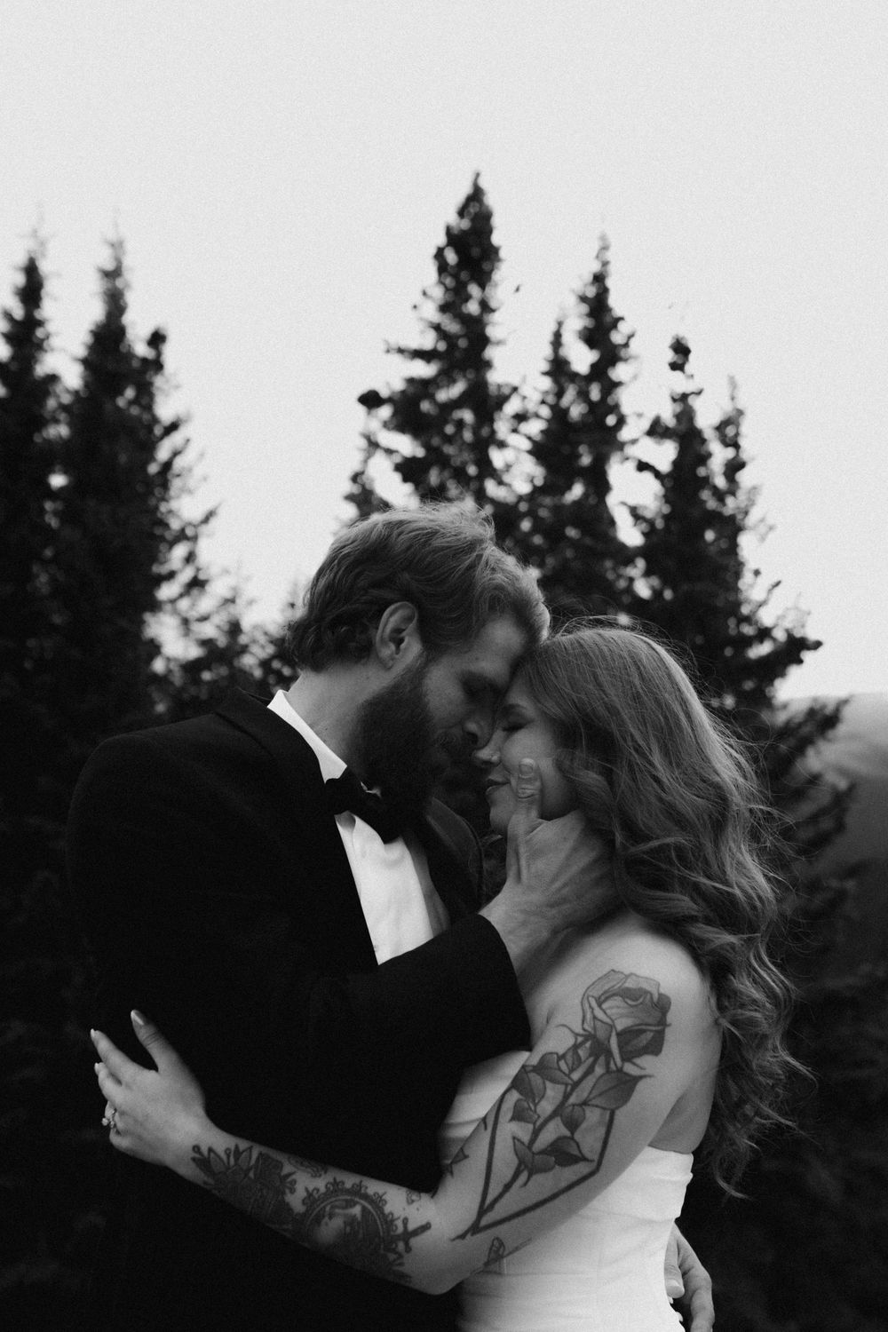 Intimate black and white portrait of a couple sharing a kiss outdoors.