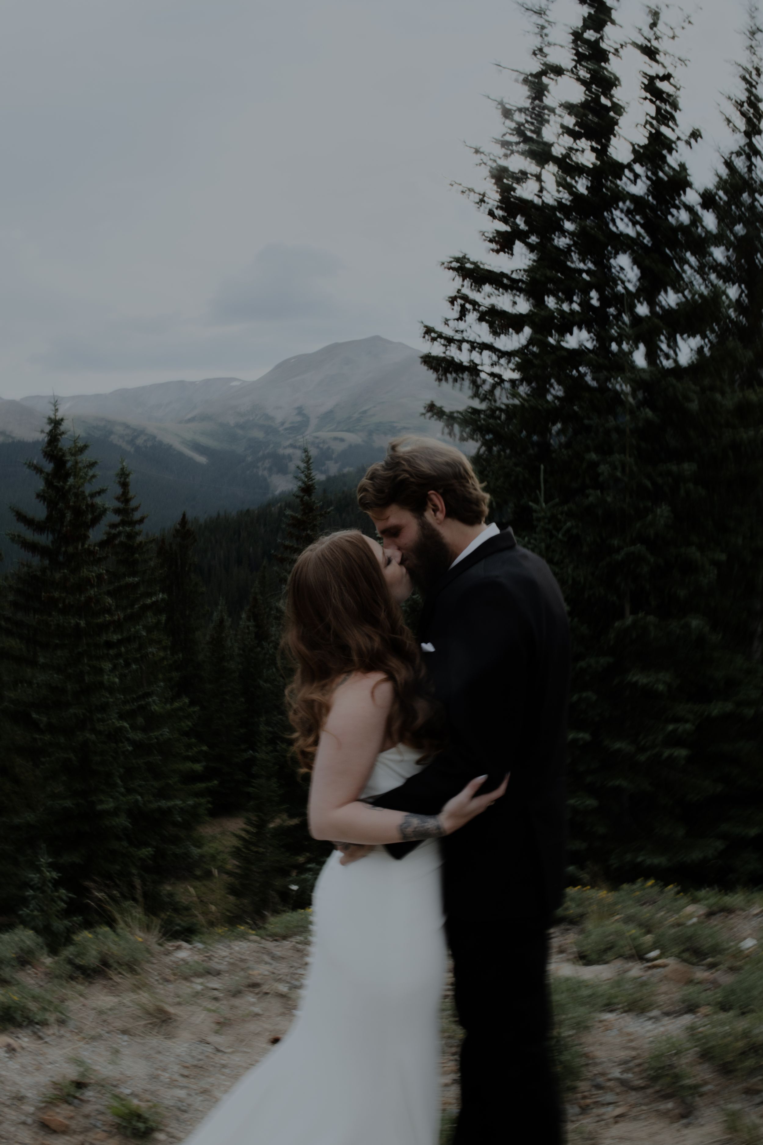 Wedding couple shares an intimate moment with mountain peaks in the background.