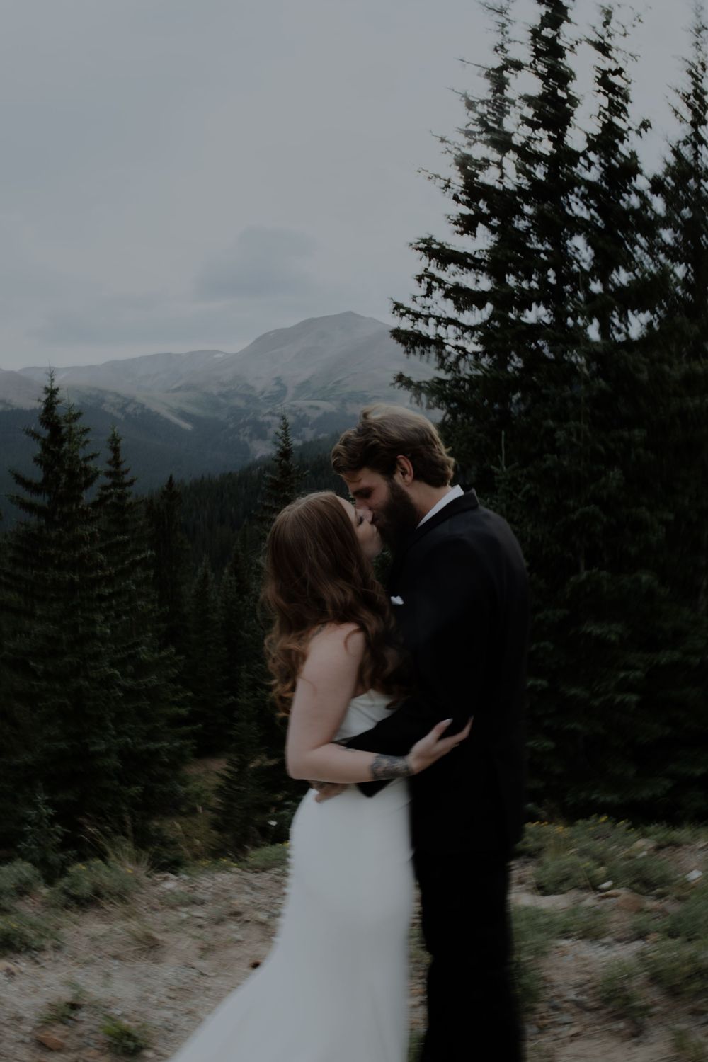 Wedding couple shares an intimate moment with mountain peaks in the background.