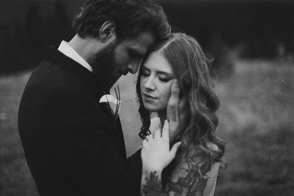 A romantic black and white wedding portrait captures an intimate moment between newlyweds.