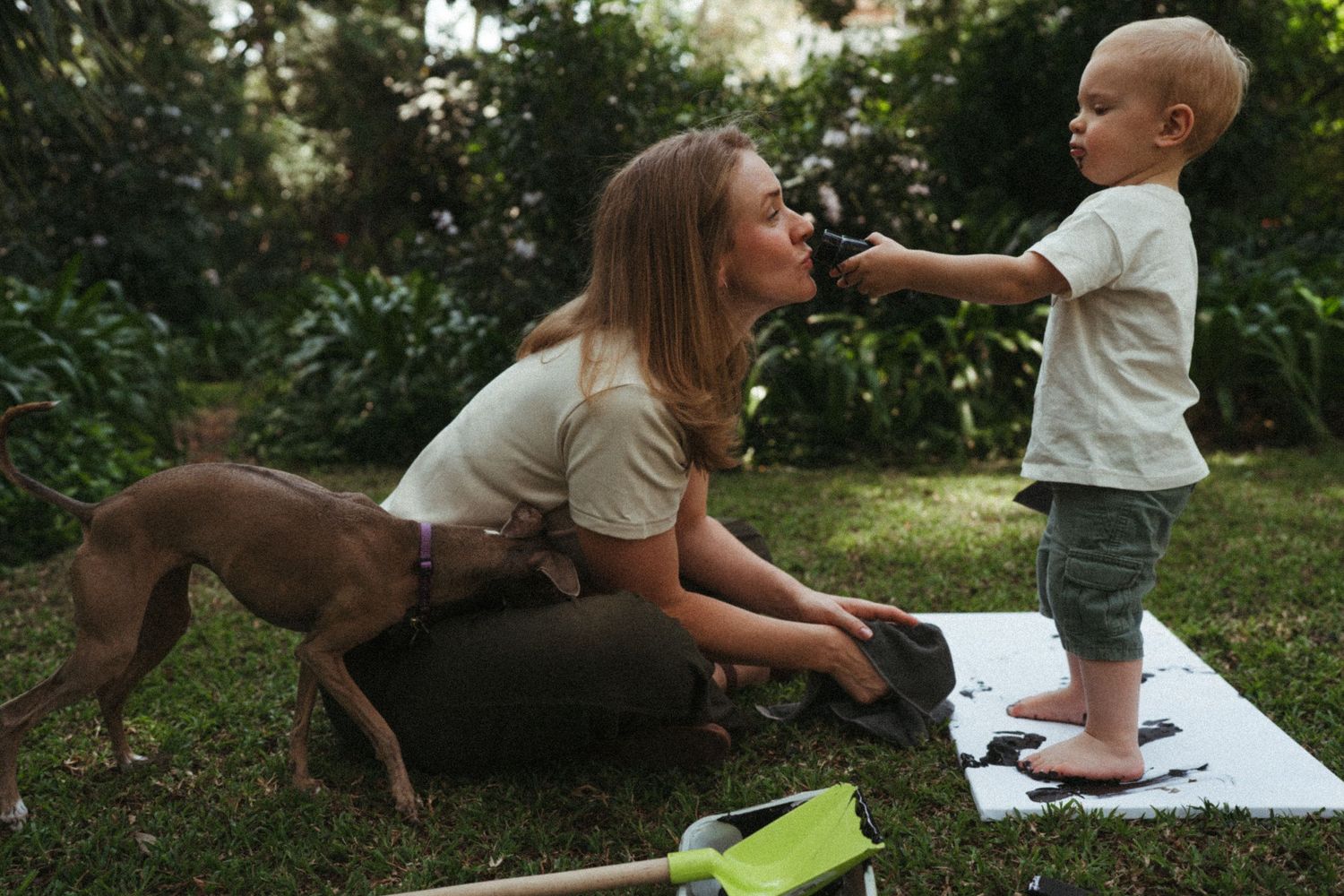 Family playing and having fun with their dog on a sunny day outdoors.