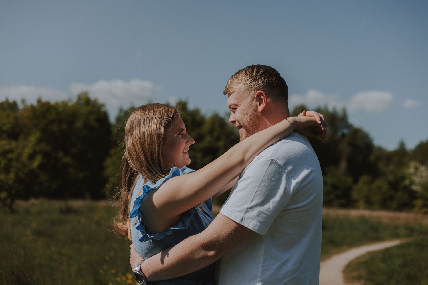 Couple embracing in a scenic outdoor setting during golden hour. Engagement Shoot