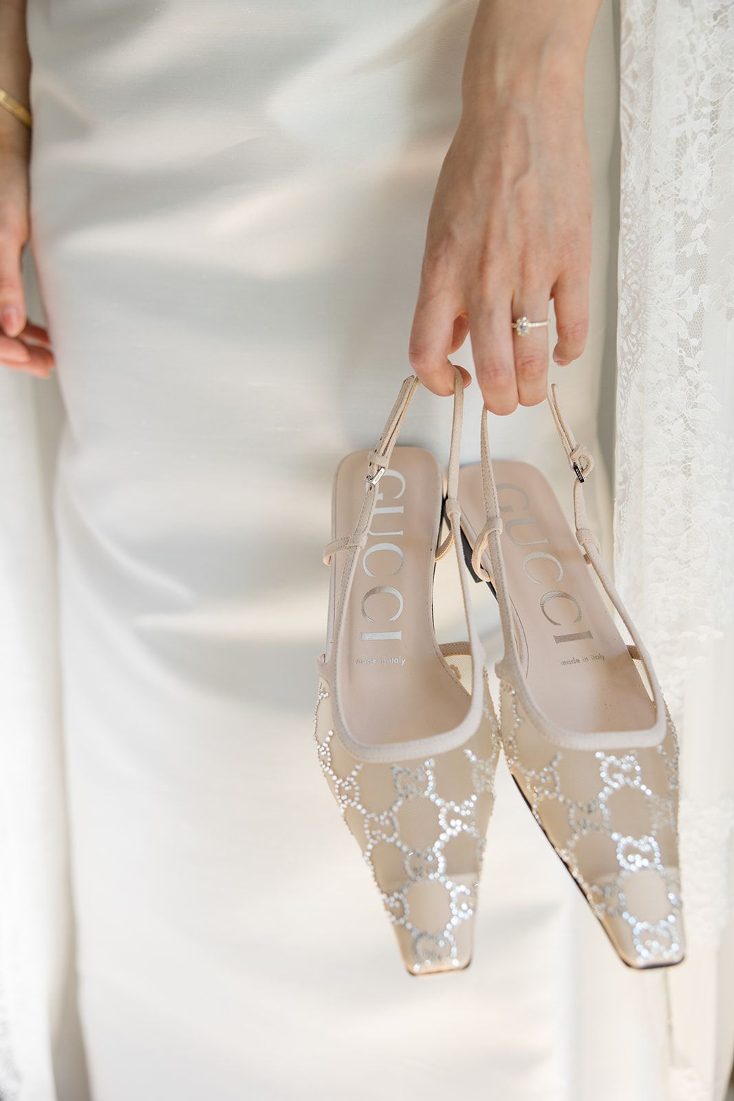 A pair of elegant beige designer shoes with monogram pattern being held against a white background.