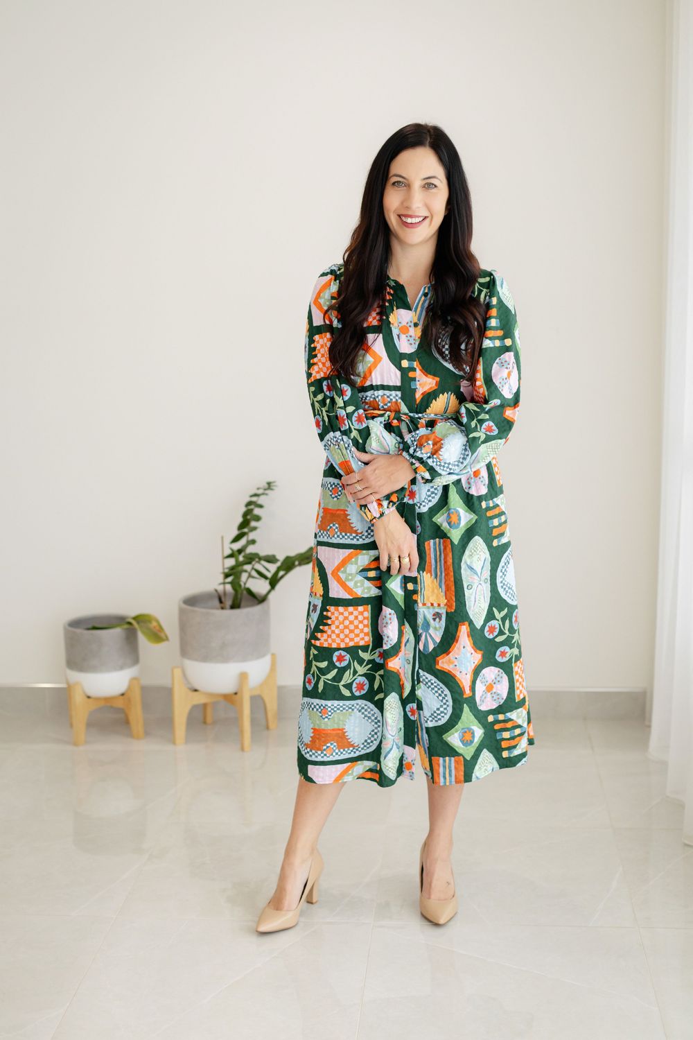 Branding Photography Session in a colorful patterned midi dress with beige heels against a white wall
