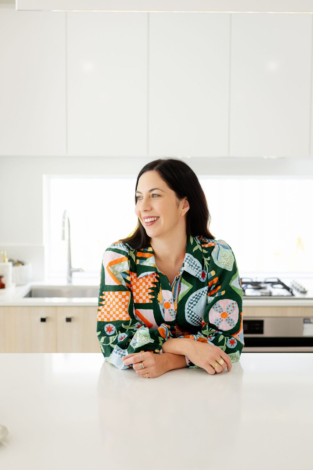 A woman leans on a white kitchen counter in a Creative Maison photo shoot location